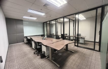 Modern coworking space featuring open desks, glass partitions, and ample natural light.