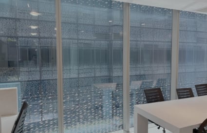Bright coworking space with modern desks and ergonomic chairs, enhanced by expansive glass walls.