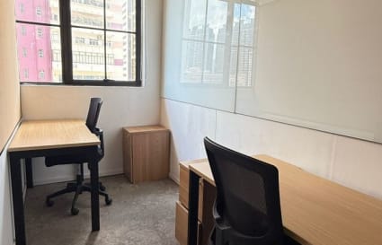 Bright coworking space with modern desks, ergonomic chairs, large windows, and sleek whiteboard.