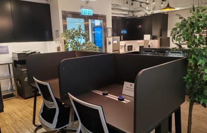 Flexible coworking space with private work pods, modern lighting, and a cozy atmosphere.