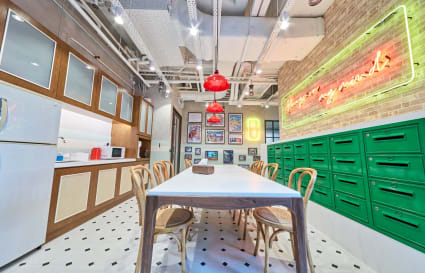 Vibrant coworking space with modern kitchen, ample seating, and artistic decor. Ideal for collaboration.