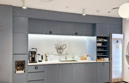 Modern kitchenette with coffee station and ample storage, ideal for a dynamic coworking atmosphere.