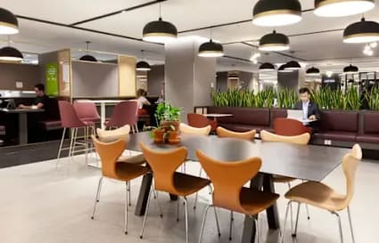 Modern coworking space with stylish seating, lush greenery, and ample lighting. Perfect for collaboration.
