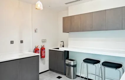 Modern kitchenette with sleek cabinetry, bar seating, and bright lighting—ideal for breaks in DMCC.