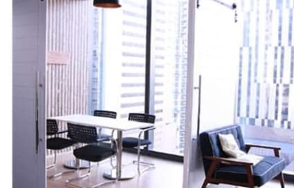 Bright, modern space with a meeting table, cozy seating, and cityscape views. Perfect for collaboration.