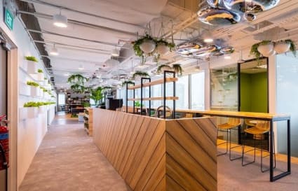 Modern coworking space with stylish seating, vibrant greenery, and ample natural light.