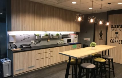 Modern coworking kitchen with sleek cabinetry, ample seating, and ambient lighting in Collyer Quay.