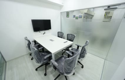 Sleek meeting room with glass walls, equipped with a TV and ergonomic chairs. Ideal for productive sessions.