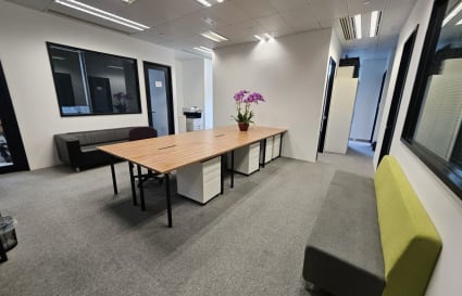 Modern coworking space with natural light, spacious desks, and comfortable seating.