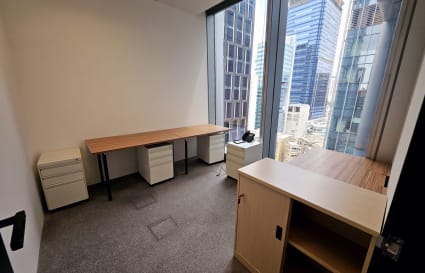 Bright coworking space with a city view, featuring modern desks and ample storage.