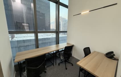 Bright coworking space with large windows, modern furniture, and city views.