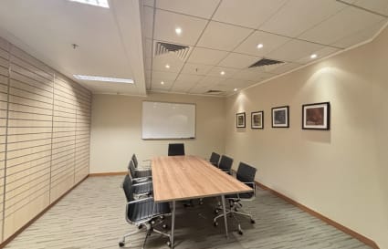 Modern conference room with sleek chairs, wooden table, and ample lighting. Ideal for meetings.