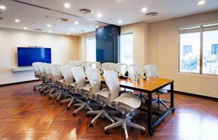 Elegant conference room with modern seating, large screen, and abundant natural light.