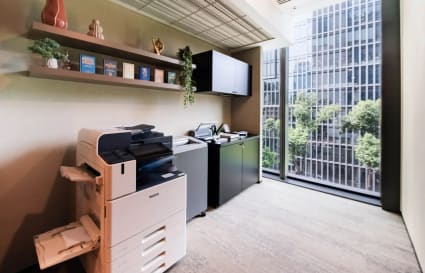 Bright, modern coworking area with copier and storage, featuring striking city views.