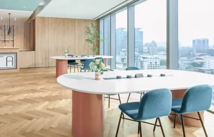 Bright coworking space with panoramic city views, elegant furnishings, and natural light.