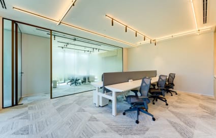 Modern coworking space with sleek desks, ergonomic chairs, and bright, ambient lighting. Ideal for collaboration.