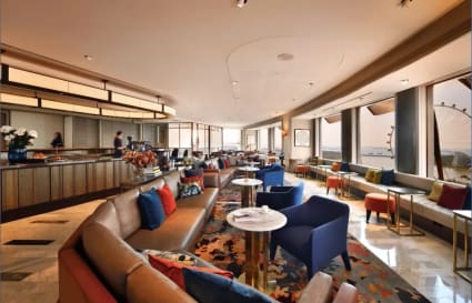 Elegant coworking space with plush seating, vibrant decor, and panoramic city views.