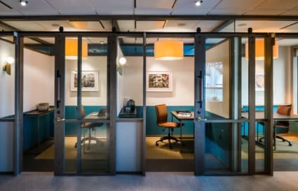 Stylish glass-partitioned offices with modern lighting, perfect for collaboration and privacy.