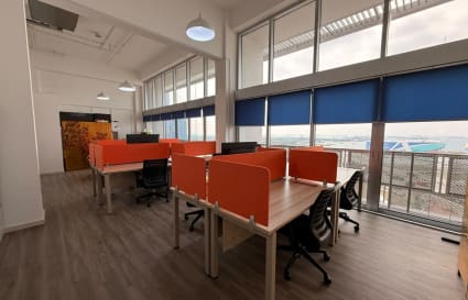 Bright coworking space with vibrant partitions, modern desks, and expansive city views.