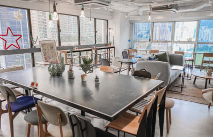 Bright coworking space with modern decor, ample natural light, and vibrant city views.