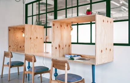 Modern coworking space with wood desks, cozy chairs, and vibrant lighting. Ideal for productivity.