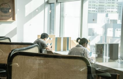 Bright coworking space with ample seating and large windows overlooking the cityscape.