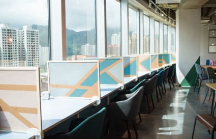 Modern coworking space with city views, bright natural light, and stylish workstations.