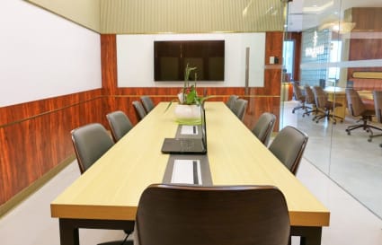 Modern coworking space with sleek meeting tables, ample seating, and a large screen for presentations.