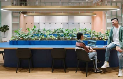 Modern coworking space with lush greenery, ample seating, and collaborative atmosphere.