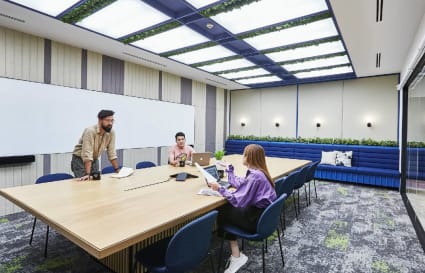 Modern coworking space with a large meeting table, ample seating, and abundant natural light.