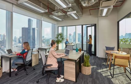 Bright coworking space with skyline views, modern desks, and a stylish lounge area in Bangkok.