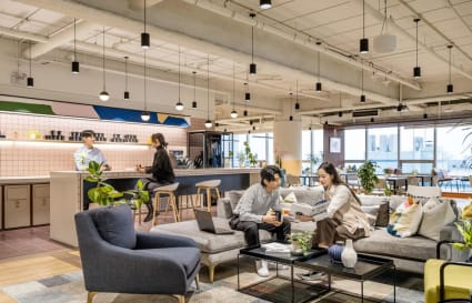 Modern coworking space with cozy seating, vibrant decor, and a sleek kitchen area. Ideal for networking.