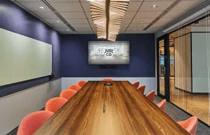 Modern meeting room with elegant wood table, vibrant seating, and advanced AV setup in Gateway Drive.