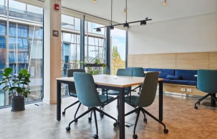 Bright and modern coworking space with natural light, comfortable seating, and greenery.