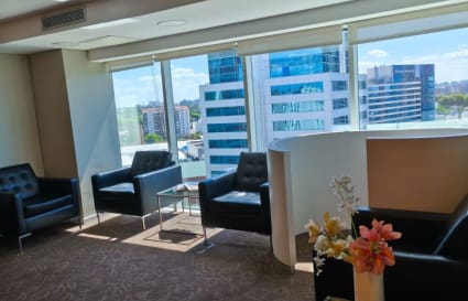 Modern coworking lounge with natural light, city views, and comfortable seating.