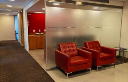 Stylish coworking space with modern red seating and frosted glass walls in Montevideo.