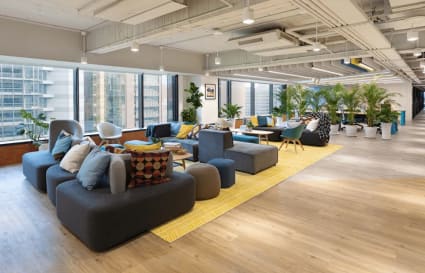Bright, open coworking space in Taipei with modern seating, natural light, and lush greenery.