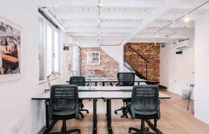 Bright coworking space with exposed brick, modern seating, and natural light. Perfect for productivity.