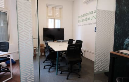 Modern coworking space with sleek meeting room, ergonomic chairs, and natural lighting.