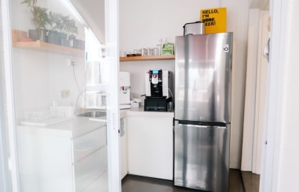 Modern kitchenette with sleek fridge and coffee machine, ideal for coworking breaks.