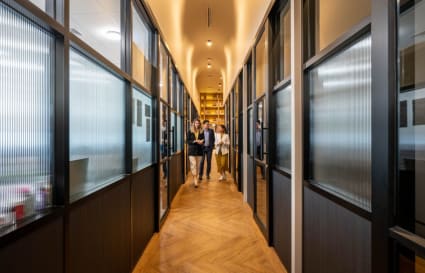 Modern office hallway with sleek glass partitions and warm lighting on Rama I Road.