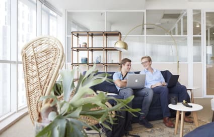 Bright coworking lounge with comfortable seating, natural light, and modern decor.