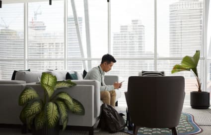 Stylish coworking space with city views, lush plants, and comfy seating. Ideal for productivity.
