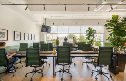 Bright, open coworking area with stylish chairs and greenery. Ideal for collaboration and focus.