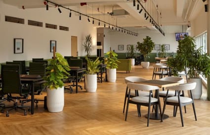 Spacious coworking area with lush greenery, ample seating, and natural light. Ideal for collaboration.