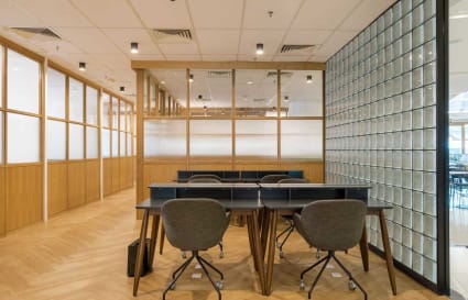 Bright coworking space with modern furniture, ample seating, and sleek glass dividers.
