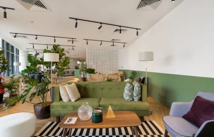 Vibrant coworking space with cozy seating, lush greenery, and ample natural light. Perfect for creativity.