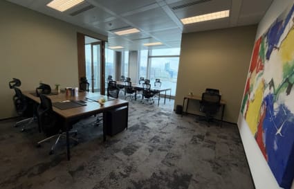 Modern coworking space with city views, sleek desks, ergonomic chairs, and vibrant artwork.