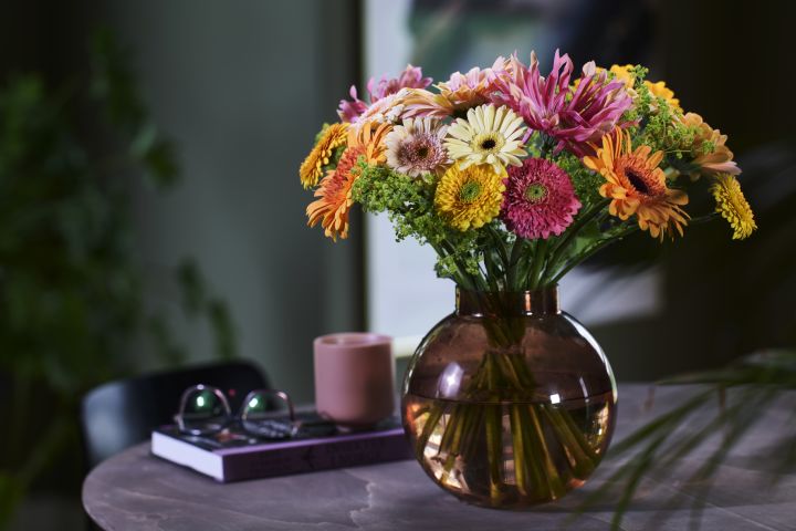Fargerik bukett med blomster i en rund glassvase