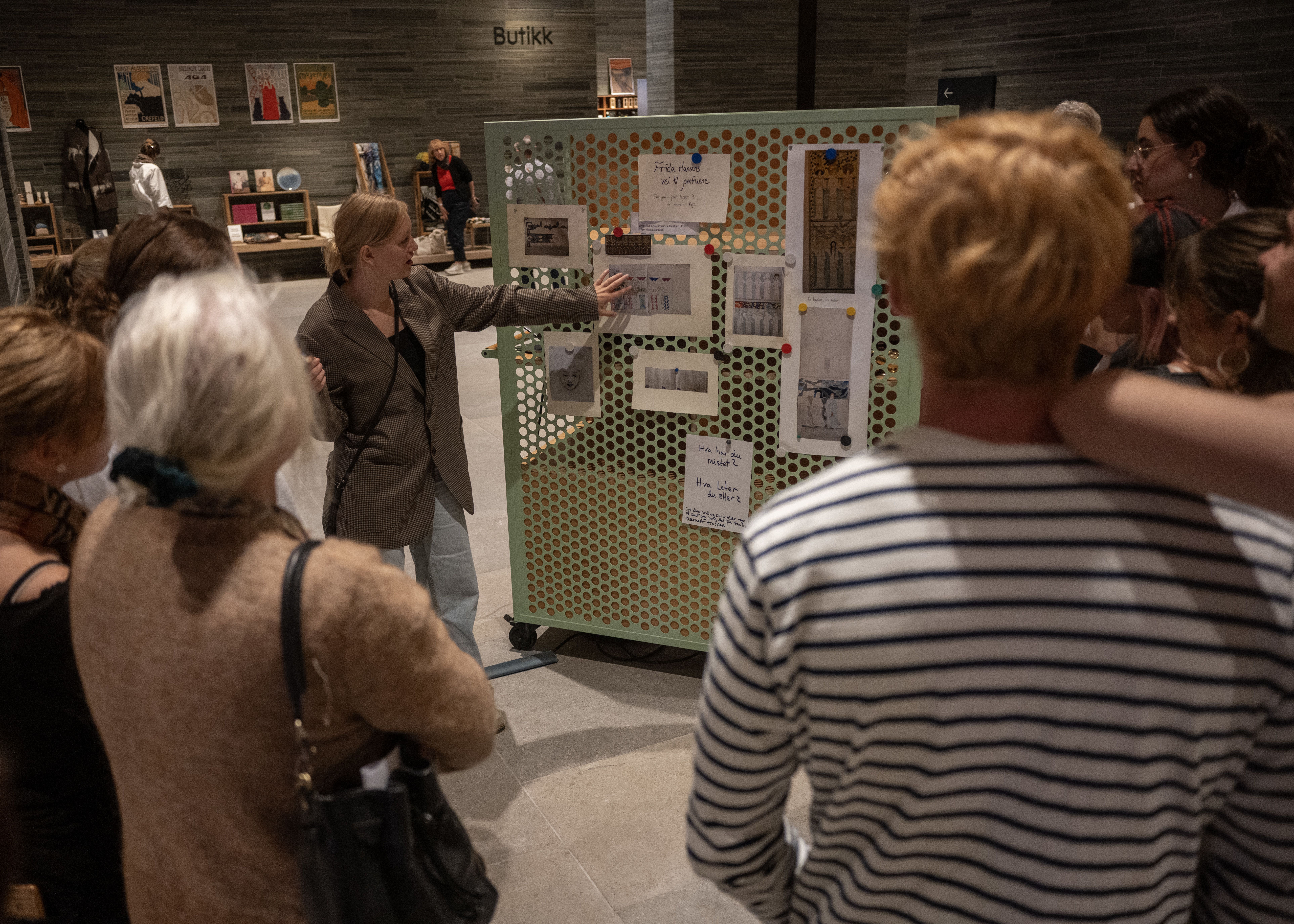 Adine forteller og peker på en oppslagsvegg